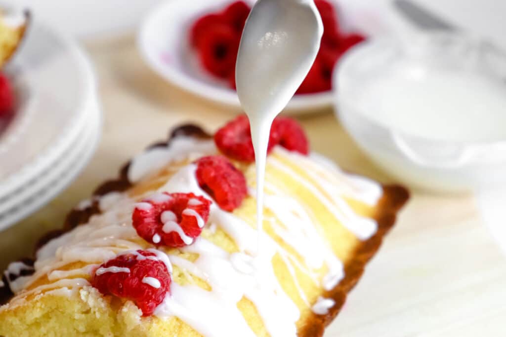 drizzling icing on raspberry breakfast cake