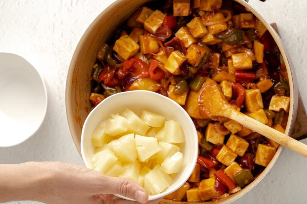 sweet and sour tofu in the pan adding pineapple