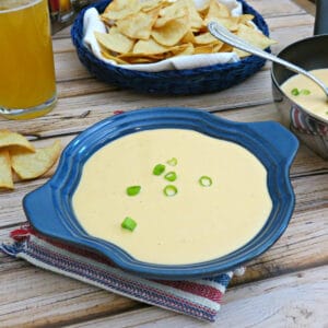 bowl of beer cheese dip with pita chips and glass of beer