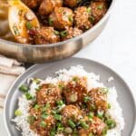 Asian meatballs on a bed of rice with a pan of meatballs in the background